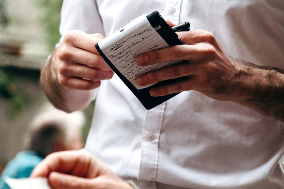 Waiter holding notepad taking an order